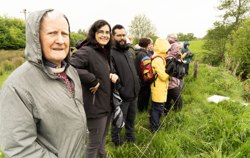 11 Bring me to the River - Columban Missionaries Group of hikers in rain jackets standing along a grassy meadow outdoors, facing the camera.