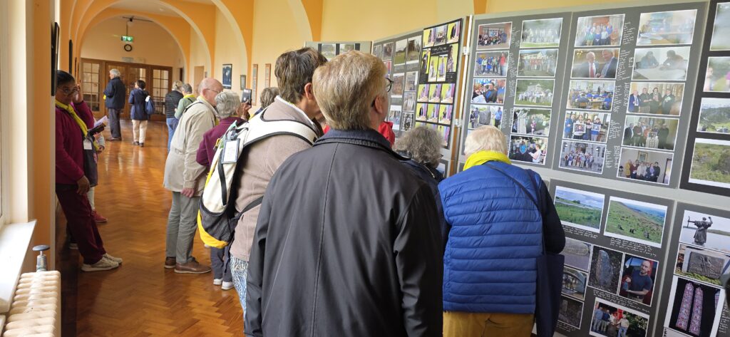 Luxeuil Pilgrims5 - Columban Missionaries Visitors study a wall of photo boards in a bright hallway exhibit.
